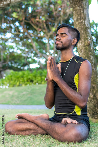Young yoga man practitioners doing yoga on nature. Asian indian yogis man on the grass in the park. Bali island.