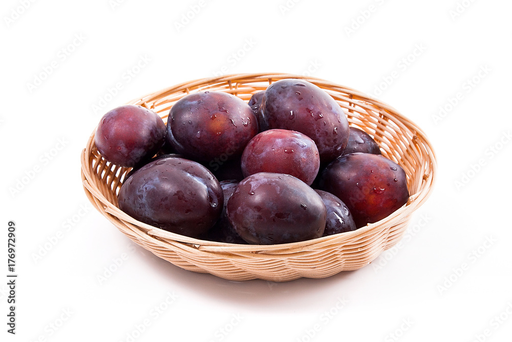 Yellow wooden basket with ripe plums isolated on a white background.. Yellow wooden basket with ripe plums isolated on a white background..