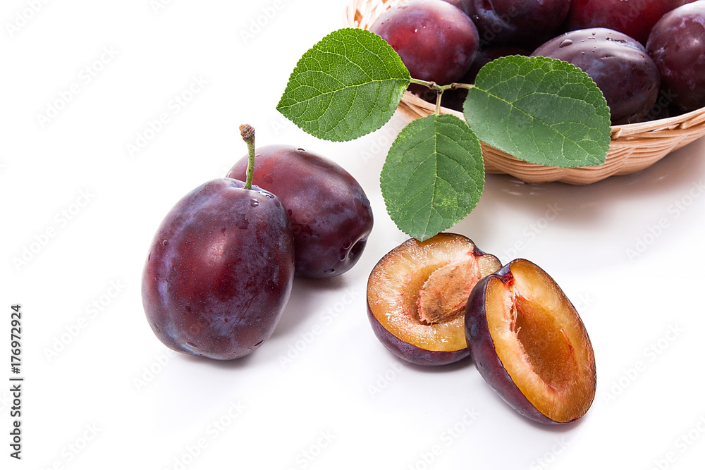 Yellow wooden basket with ripe plums, whole and half ripe plums isolated on a white background.. Yellow wooden basket with ripe plums, whole and half ripe plums isolated on a white background..
