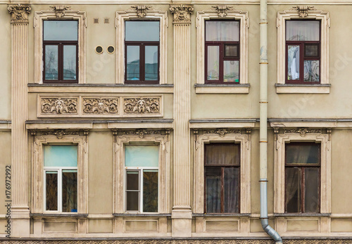 Several windows in a row and balcony on facade of urban apartment building front view, St. Petersburg, Russia