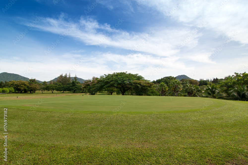 Green grass Golf field in big city park in a sunny day with blue sky and clouds for background. 