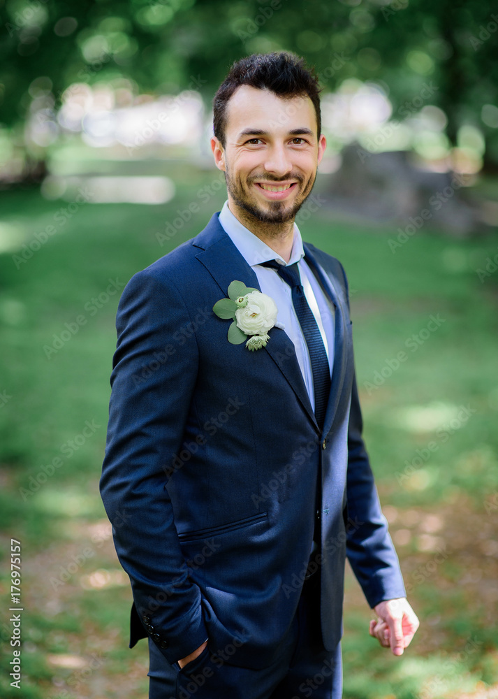 Handsome brunette groom stands on green lawn Handsome brunette groom stands on green lawn