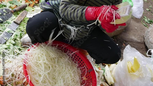 Closeup of a woman shreds green papaya in a basket in the local market photo