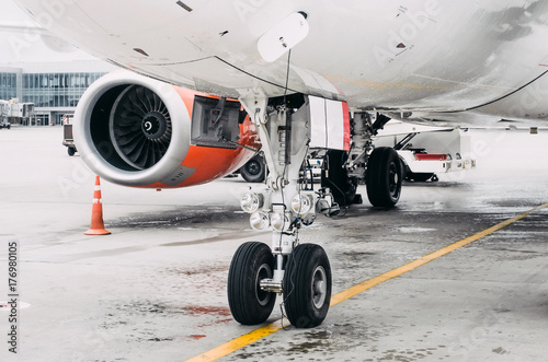 Front landing gear and engine airplane parking in the airport.