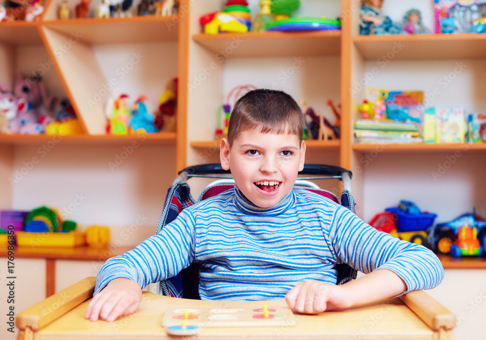 Fototapeta premium cheerful boy with disability at rehabilitation center for kids with special needs, solving logical puzzle