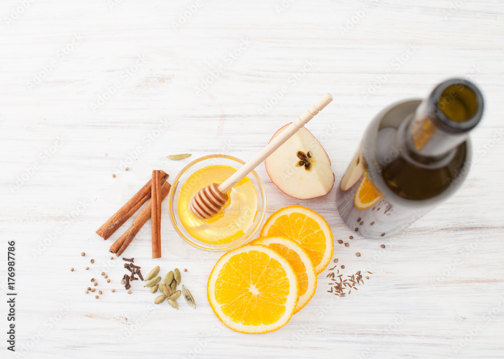 A bottle of wine, slices of orange, honey, cinnamon to mulled wine on white A bottle of wine, slices of orange, honey, cinnamon to mulled wine on white