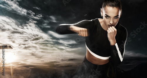 Fototapeta Naklejka Na Ścianę i Meble -  A strong athletic, woman boxer, boxing at training on the sky background. Sport boxing Concept with copy space.