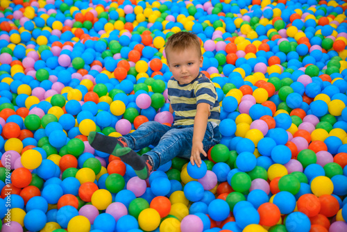 A boy in the playing room with many little colored balls photo