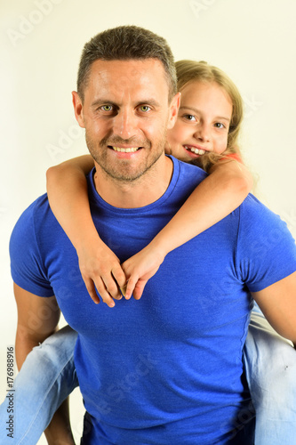 Schoolgirl sits on dads back. Daughter and father hug