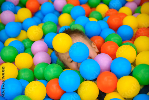 A boy in the playing room with many little colored balls