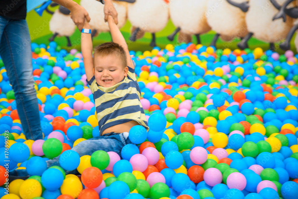 A boy with mother in the playing room with many little colored balls A boy with mother in the playing room with many little colored balls