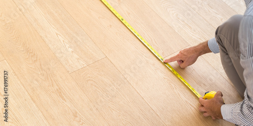 Architect taking measures of the new hardwood floor. Home and maintenance concepts