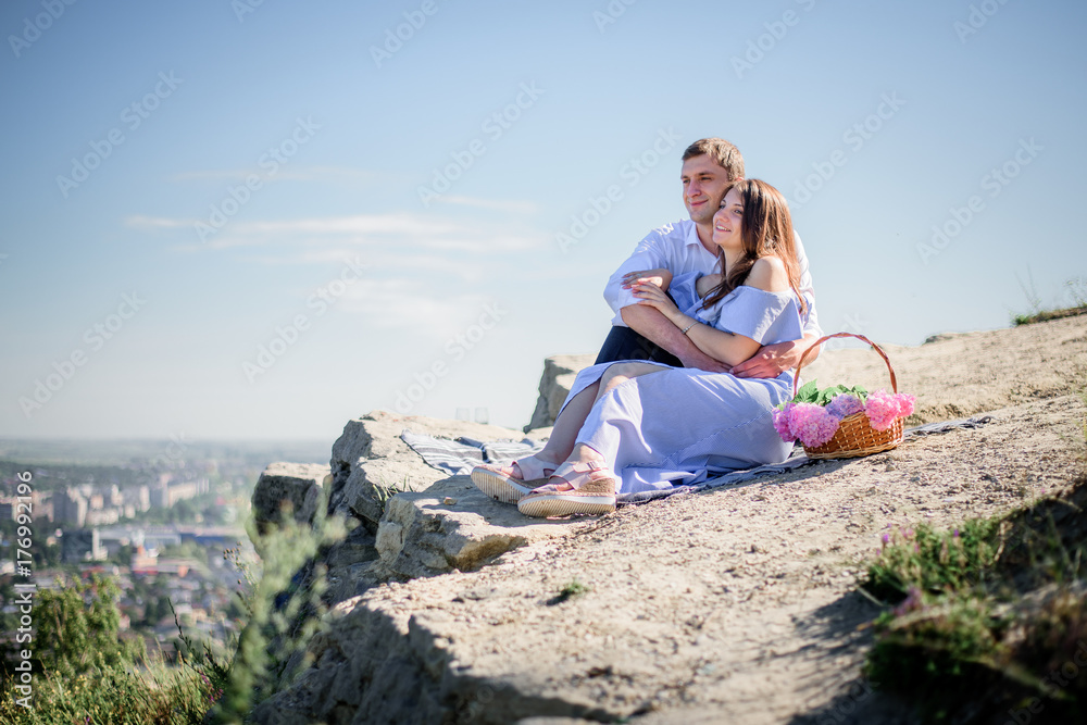 Charming couple sits with glasses of champagne on the rock