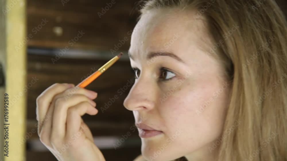 Beautiful woman in towel, paints her eyebrows in front of mirror Beautiful woman in towel, paints her eyebrows in front of mirror