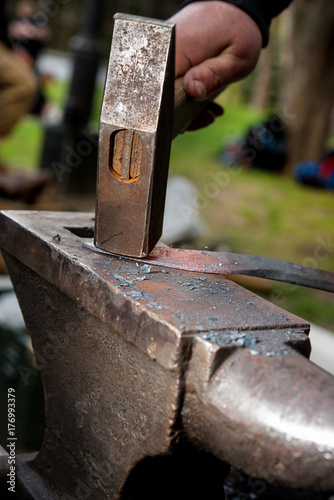 Master a man forges a sword from a red-hot metal on an anvil photo