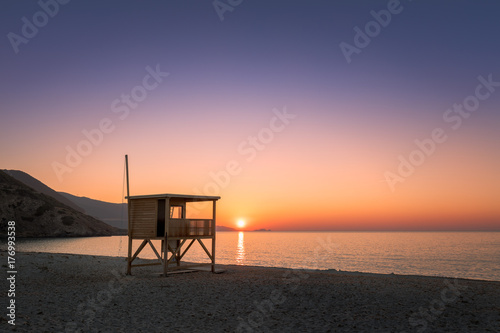 Sun setting behind lifeguard tower on Ostriconi beach in Corsica