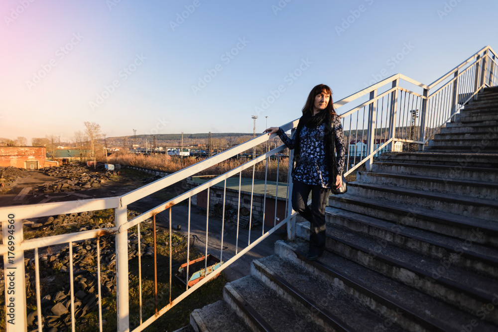 the woman walks the stairs of the crossing through the railway