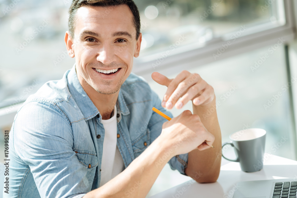 Cheerful brunette male sitting at his workplace Cheerful brunette male sitting at his workplace