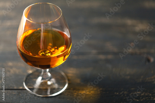 Glass of brandy on black background