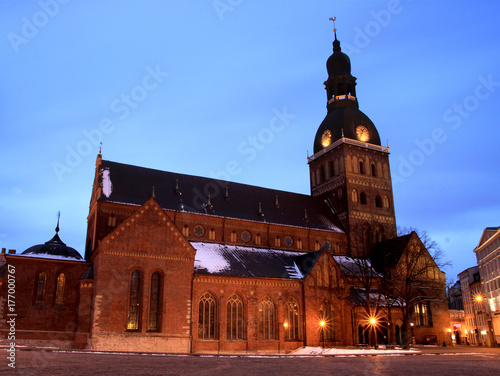 Riga, Latvia. View Of Dome Square And Dome Cathedral In Evening Illumination Under Blue Sky. Winter time, first snow