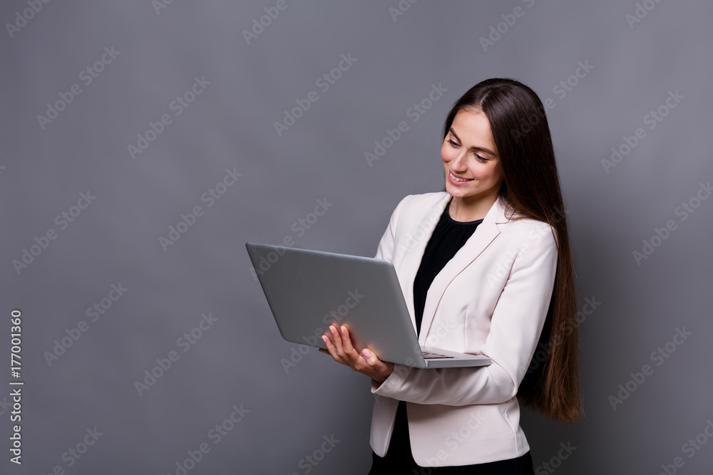 Smiled business woman with laptop on gray background Smiled business woman with laptop on gray background
