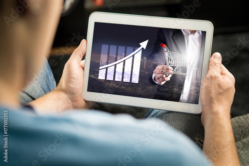 Statistics, analytics and financial report on tablet screen. Success and growth concept. Entrepreneur using business application and doing market analysis with smart mobile device at home.