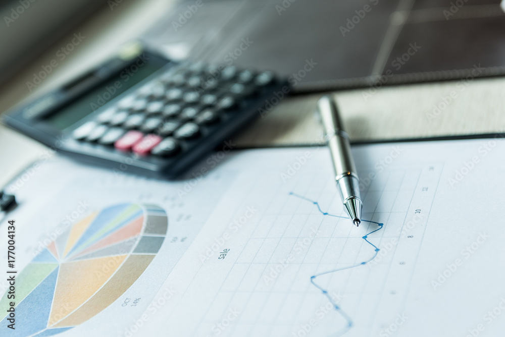 ballpoint pen on the graphic document and calculator, finance business working online concept. ballpoint pen on the graphic document and calculator, finance business working online concept.