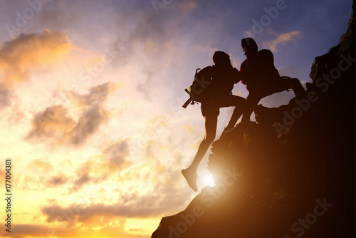 Asia couple hiking help each other silhouette in mountains with sunlight.