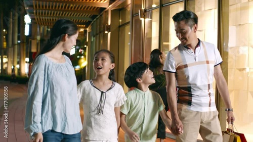asian family of 4 walking & shopping outside a shopping mall at night in slow motion