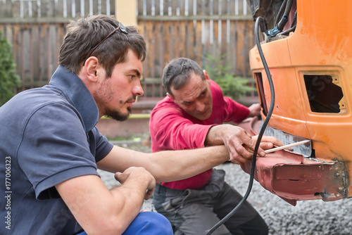 Two men working to restore an old van