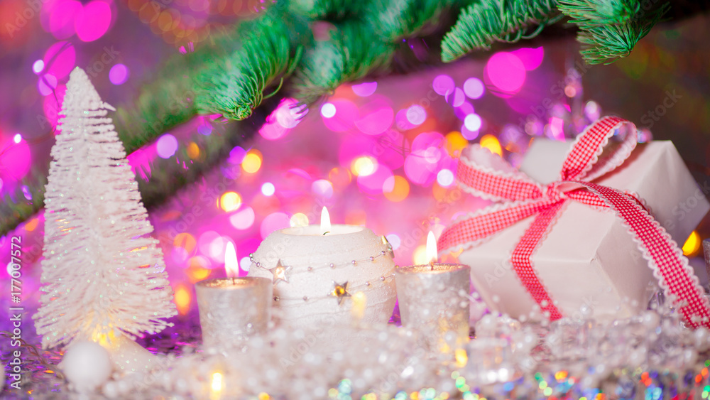 Christmas card. Background on a theme of New Year's  party. Decorated fir-tree with gifts and candles on the background of colorful festive lights. A magical evening.