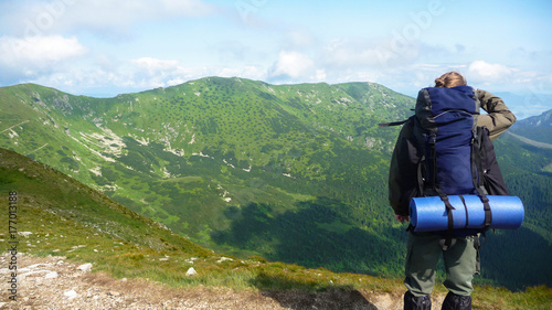 Man standing in mountains with big backpack and watching nature