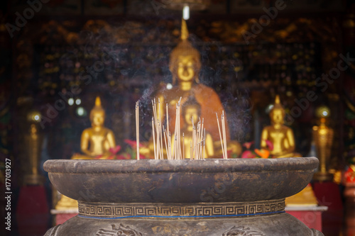 Smoke incense sticks in the pot with blur golden Buddha background