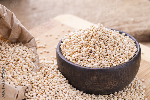 pile of quinoa seeds in container on wood