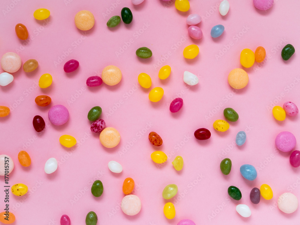Many scattered colorful sweets, candies, lollipops on a pink background
