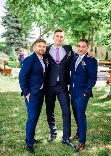 Stylish groom and groomsmen in blue suits pose in the garden