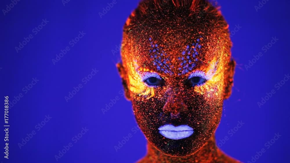 Portrait of beautiful girl with ultraviolet paint in color light
