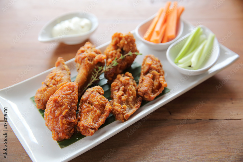 Buffalo wings barbecue chicken with carrots and cucumbers on wood background Buffalo wings barbecue chicken with carrots and cucumbers on wood background