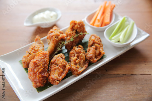 Buffalo wings barbecue chicken with carrots and cucumbers on wood background