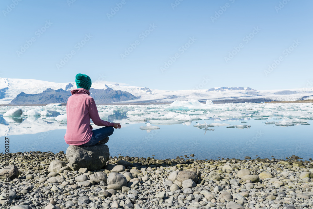 Mujer joven practicando yoga a la orilla del lago glaciar Jokulsarlon en Islandia
