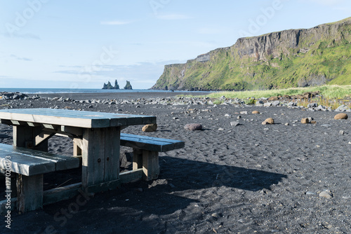 Mesa de picnic en la playa de Vik con las impresionantes formaciones rocosas Reynisdrangur al fondo. Islandia © Esther Pueyo
