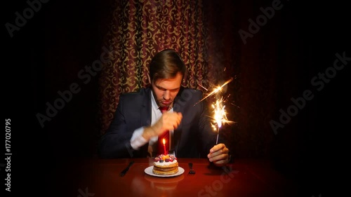 a lone man celebrates a holiday, he sits alone at a table with a cake and a candle. 4k, slow motion photo