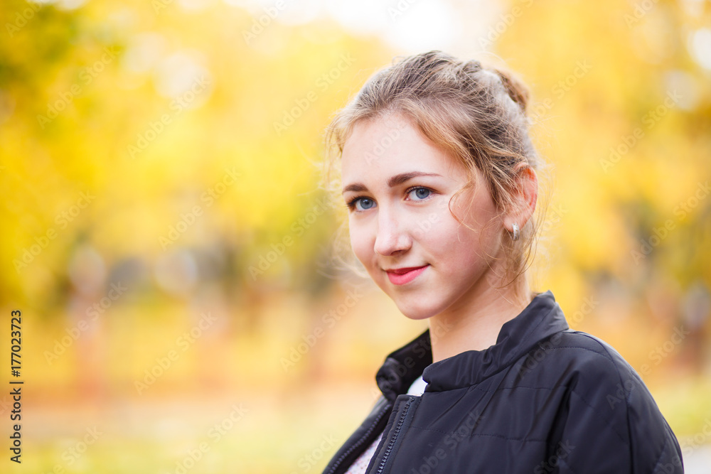 Young smiling teenage girl standing in autumn park Young smiling teenage girl standing in autumn park
