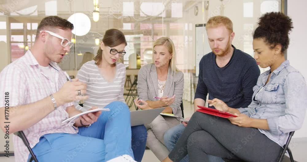Group of colleagues in casual clothes sitting in office, discussing new work strategy and making notes on laptop and tablet. Group of colleagues in casual clothes sitting in office, discussing new work strategy and making notes on laptop and tablet.
