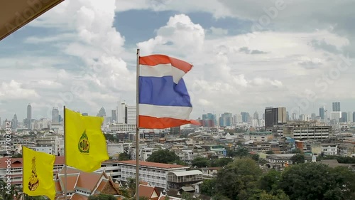 Thailand state flag fluttering in the wind on the top of Wat Saket Golden Mountain . Bangkok panorama view on background. Thailand. photo