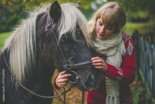 a girl is preparing her horse for a ride photo
