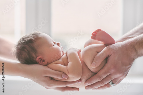Mother and father holding their newborn baby in their hands.