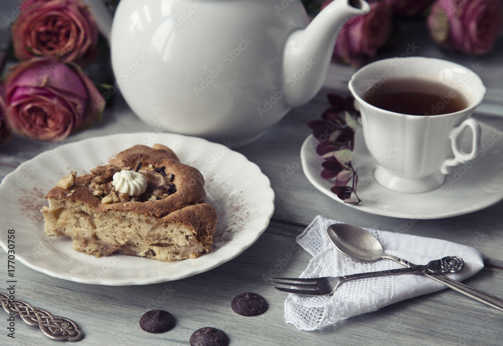 Apple pie charlotte with cinnamon and a cup of tea in the style of a shabby chic. Selective focus, shallow depth of field, close up