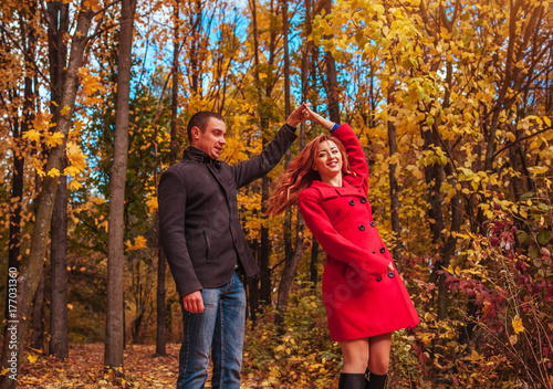 Young couple dances in autumn forest among colorful trees