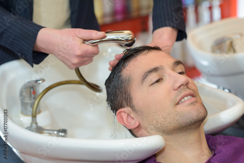 barber washing head client in barbershop